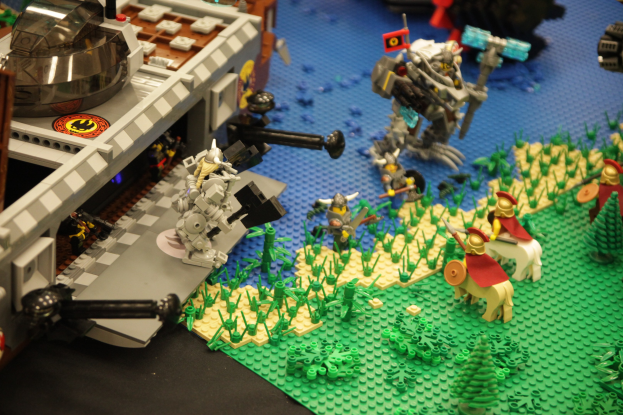 Ein Lego-Schlossmodell mit verschiedenen Lego-Teilen, darunter Spielzeuge, Pflanzen und andere Gegenstände, die auf seiner Oberfläche verstreut sind.