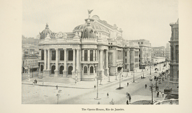 Schwarzes und weißes Foto des Opernhauses in Rio de Janeiro, ein großes Gebäude mit Säulen, Bögen und einer Statue darauf, vor einem Himmel mit Straßenelementen und Passanten.