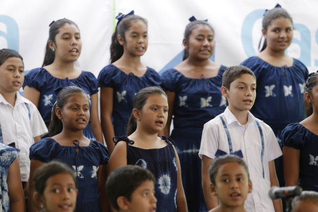 Eine Gruppe von Kindern in einem Schulchor, die gemeinsam vor einem Mikrofon singen.