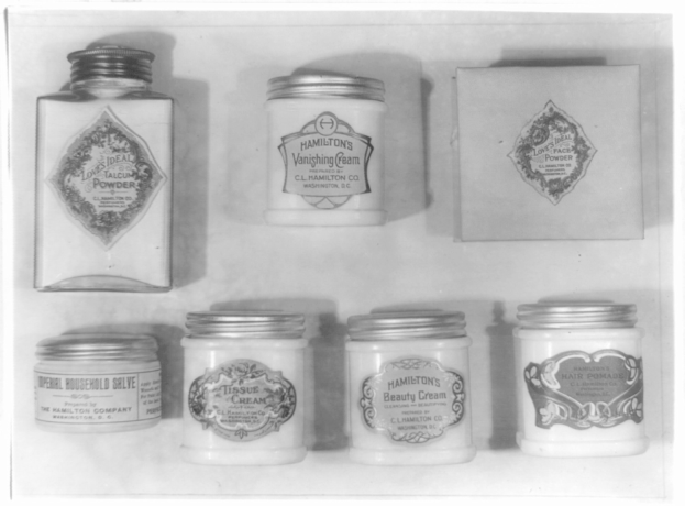 Schwarz-weiß-Foto eines Regals mit ordentlich angeordneten Sahne-Tiegeln.