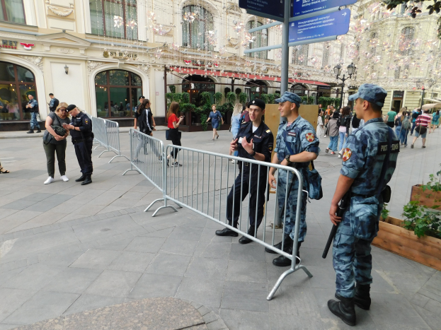 Polizeibeamte in Uniform stehen hinter Barrikaden und blicken auf eine Menge, von denen einige Mützen tragen und Waffen halten, mit Gebäuden, Bäumen und Laternen im Hintergrund während eines Anti-Terror-Einsatzes in Wien, Österreich.