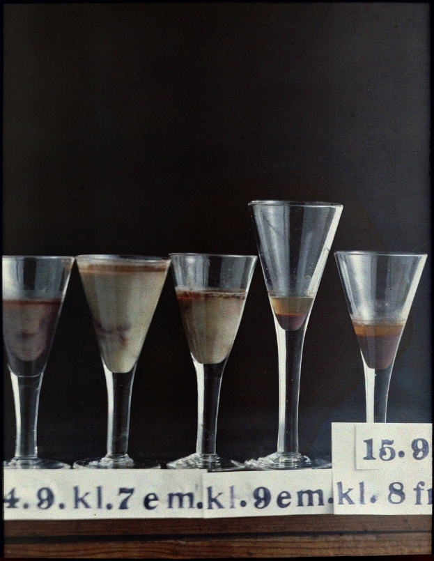 Five martini glasses in a row on a table, each numbered and filled with a different drink.