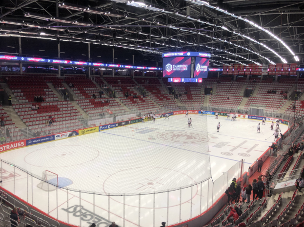 Ein Eishockeyspiel in einer großen Arena mit Zuschauern, einem Zaun um die Eisfläche, einem Display mit der Aufschrift "St. Louis Blues vs Detroit Red Wings", Metallrahmen und einer Decke mit Leuchten.