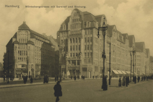 Altes Schwarz-Weiß-Foto von Fußgängern auf einer Straße in Hamburg, Deutschland, gesäumt von Gebäuden, Straßenlaternen, Lampen und Kraftfahrzeugen unter einem bewölkten Himmel.