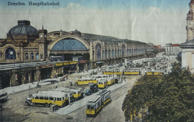 Schwarz-weiß-Postkarte des Dresdner Hauptbahnhof Bahnhofs in Deutschland, die eine belebte StraßenSzene mit Fahrzeugen, Fußgängern, Bäumen, Gebäuden und einem bewölkten Himmel zeigt.