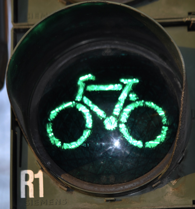 Grüne Ampel mit Fahrradsymbol vor einer Wand im Hintergrund.