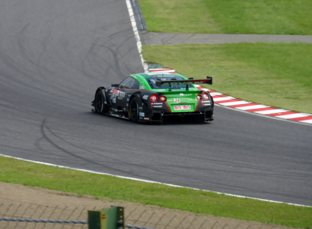 Nissan GT-R Nismo GT3 Rennauto auf der Nürburgring 24 Stunden Strecke mit grünem Gras und einem Zaun im Vordergrund.