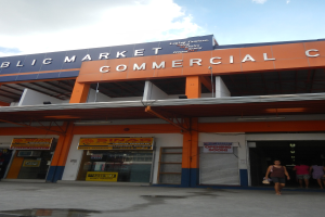 Öffentlicher Marktkomplex mit Menschen vor dem Gebäude, Text auf dem Gebäude und Himmel darüber.