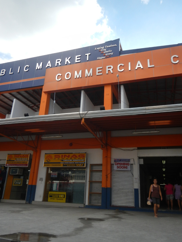 Öffentlicher Marktkomplex mit Menschen vor dem Gebäude, Text auf dem Gebäude und Himmel darüber.
