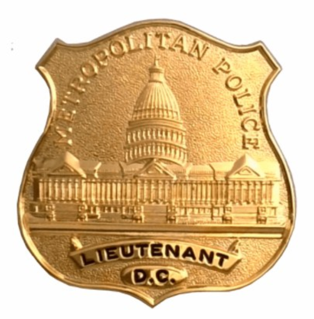 Goldenes Polizeischild mit "Leutnant DC" eingraviert, mittig auf einem weißen Hintergrund.