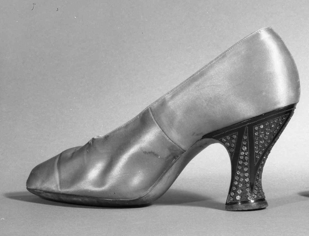 Schwarz-weiß-Foto eines Paares hochhackiger Damenschuhe aus den 1930er Jahren aus glänzendem Material.