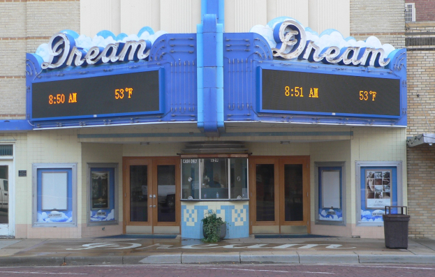 Außenansicht des Dream Theaters in St. Louis, Missouri, mit Glastüren und Fenstern, einem Namensschild, einem Müllbehälter, einem Topf mit einer Pflanze und einer Straße unten.