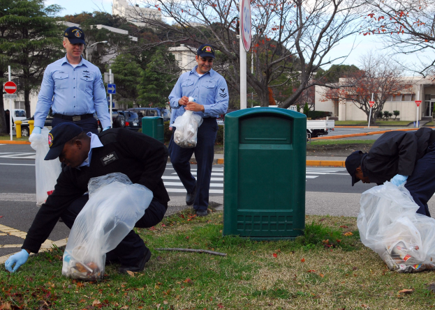 Drei Polizisten in Uniform sammeln Müll an einer Straße