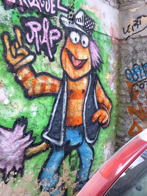 Ein rotes Auto, das vor einer mit Graffiti bedeckten Wand geparkt ist.