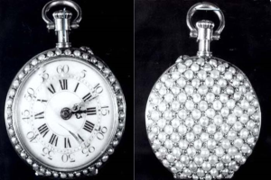 Eine silberne Taschenuhr mit Diamanten auf der Oberfläche, die ein rundes Zifferblatt mit römischen Zahlen zeigt, vor einem schwarzen Hintergrund.