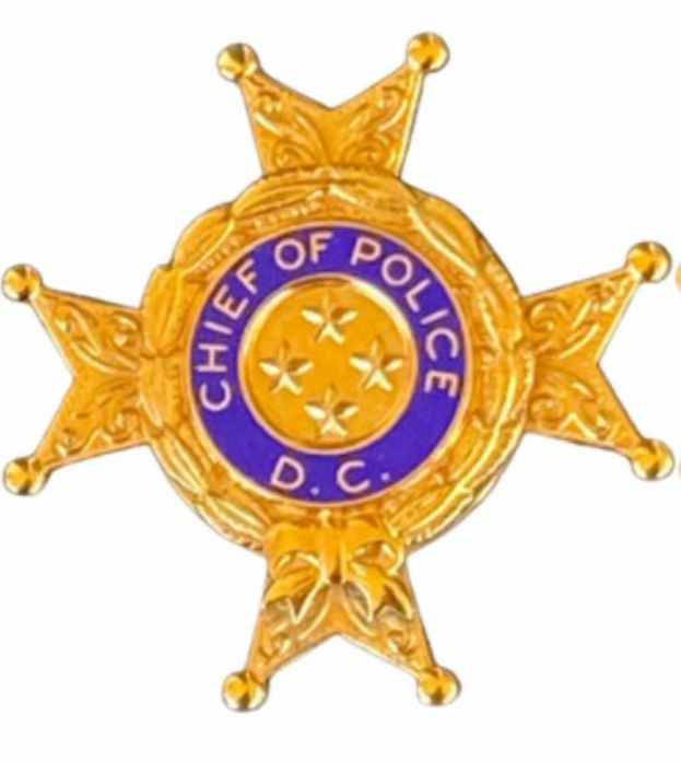 Eine goldene Polizei-Marke mit "Chief of Police" eingraviert, mittig auf einem weißen Hintergrund.