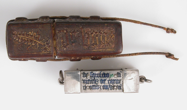 Ledertasche mit einem metallenen Pfeifeanhänger, verziert mit eingravierter Schrift.