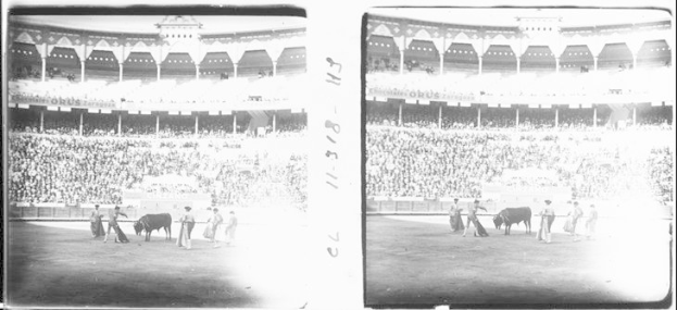 Schwarzes und weißes Foto eines Stierkampfs in einem Stadion mit Zuschauern auf den Rängen und Teilnehmern in der Arena.