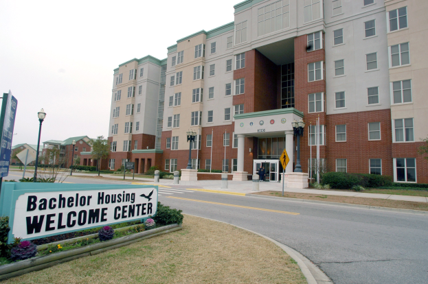 Außenansicht eines Bachelor-Unterkunfts-Willkommenszentrums mit Gebäuden, Straßeninfrastruktur, Fahrzeugen, Vegetation und einem klaren Himmel.