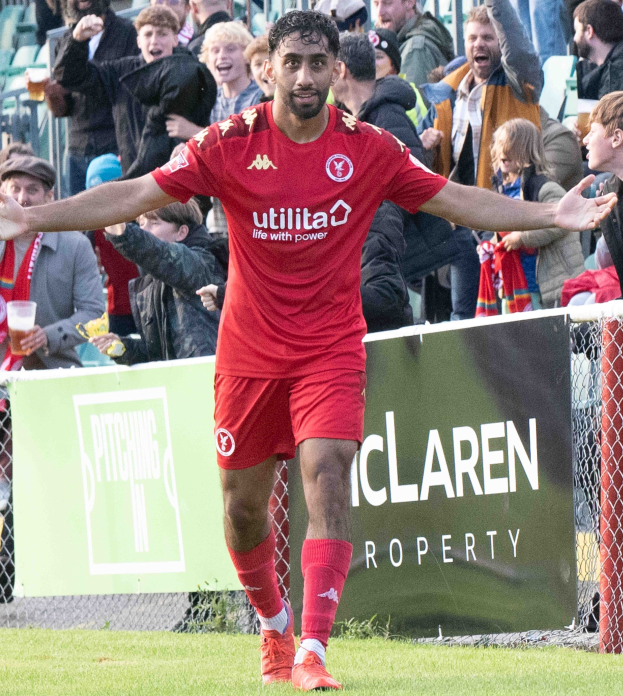 Ein Fußballspieler in roter Uniform rennt mit ausgestreckten Armen auf einem Feld, umgeben von Zuschauern, mit einem "Middlesbrough FC v Swansea City - Sky Bet Championship"-Schild im Hintergrund.