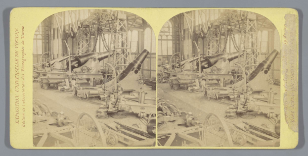 Schwarzes und weißes Foto eines Fabrikinneren mit einem gro├čen Geschütz in der Mitte, umgeben von kleineren Geschützen, Metallstangen und anderem Equipment auf dem Boden, mit Text auf der linken Seite.