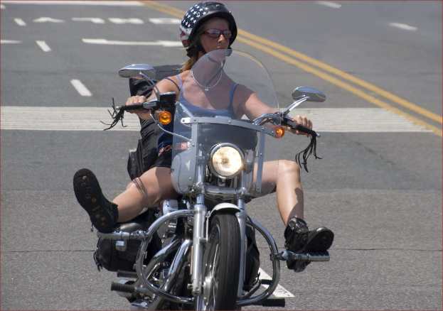 Eine Frau in einem schwarzen Helm fährt ein Fahrrad auf einer Straße.