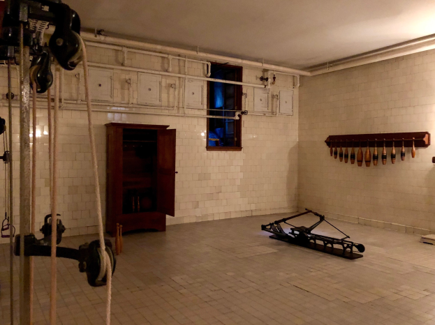 Ein unordentlicher Raum im ehemaligen Gefängnis St. Louis mit Seilen, Maschinen und anderem Equipment, mit einem Schrank, Fenster und Deckenlampe im Hintergrund.