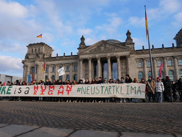 Gruppe von Menschen vor dem Reichstag in Berlin mit einem Banner, auf dem "Wir sind ein Menschenrecht" steht