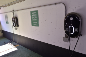 Elektrofahrzeug-Ladestationen an einer Wand in einer Tiefgarage montiert, mit Informationsschildern darüber.