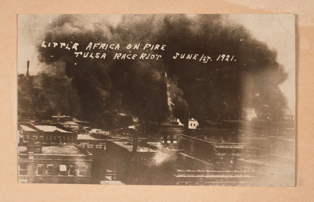 Schwarz-weiß-Foto einer Stadt mit aufsteigendem Rauch, mit Text in der Mitte und Gebäuden unten.